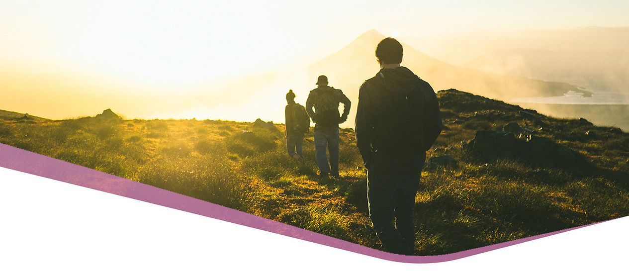 Three people walking across a sunlit mountain landscape